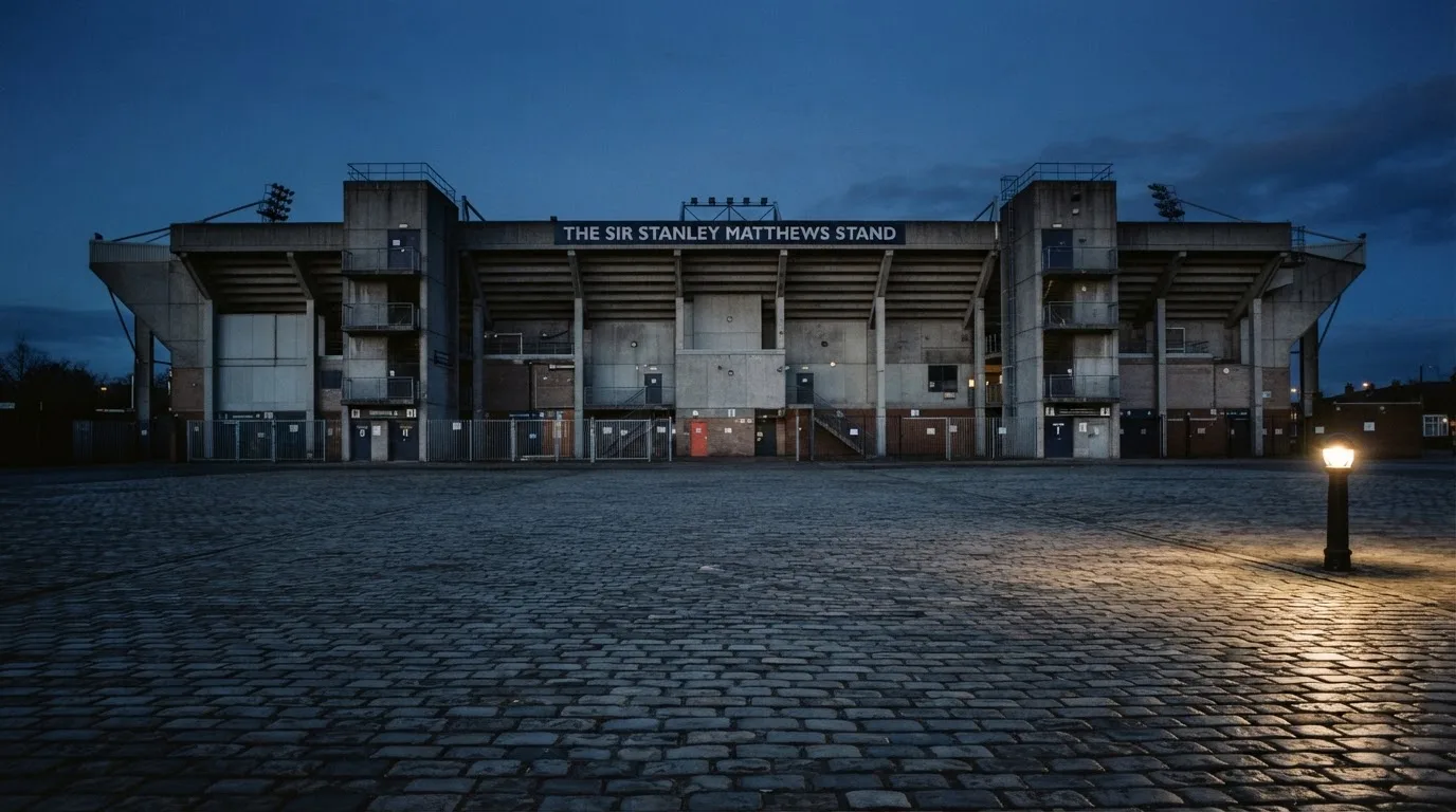 Die Rückseite einer Tribüne bei Dämmerung, davor ein menschenleerer Vorplatz mit Pflastersteinen.