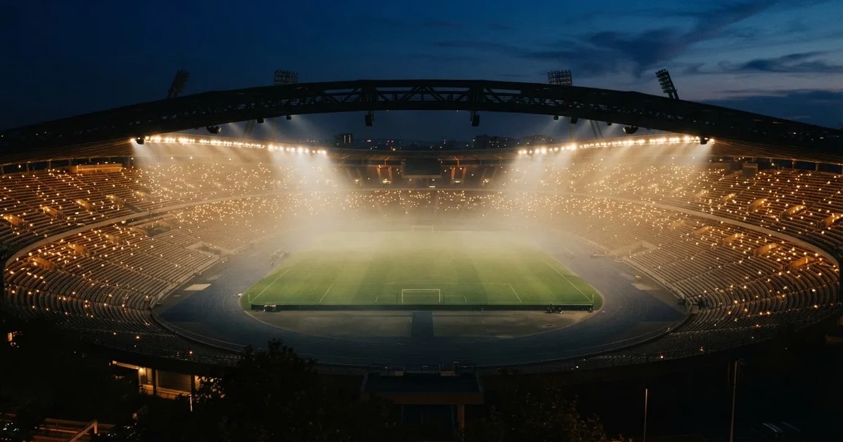 Ein leeres Stadion unter Flutlicht aus großer Entfernung gesehen, Dunst liegt über dem Rasen, die Tribünen sind nur als Lichtpunkte erkennbar.
